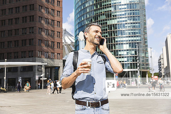 Smiling businessman talking on the phone in the city  Berlin  Germany