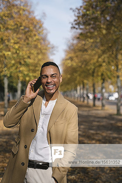 Porträt eines lachenden Geschäftsmannes am Telefon im Herbst