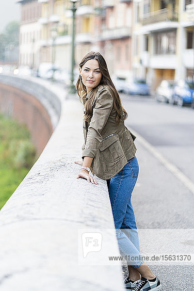 Young brunette woman looking at camera and leaning on a wall