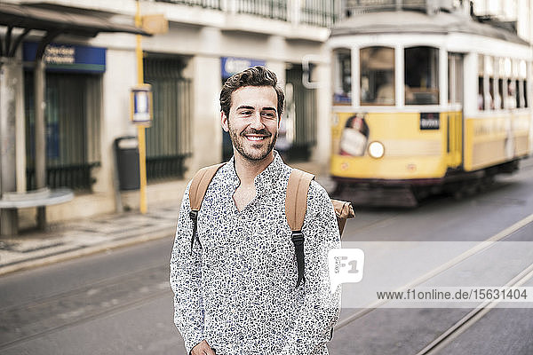 Lächelnder junger Mann mit Rucksack in der Stadt unterwegs  Lissabon  Portugal