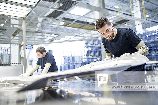 Zwei Kollegen untersuchen Bauteil in Autofabrik