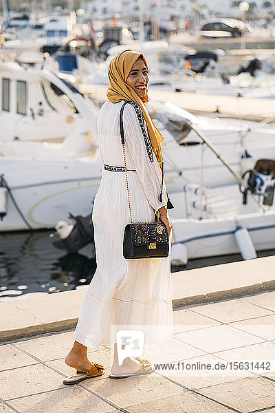Junge muslimische Frau mit gelbem Hidschab beim Spaziergang am Hafen