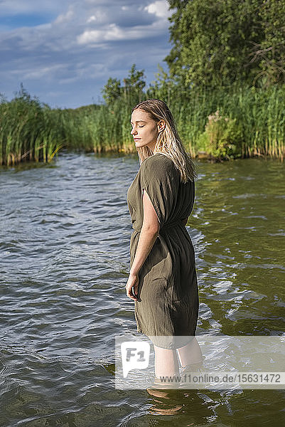 Frau mit geschlossenen Augen steht in einem See