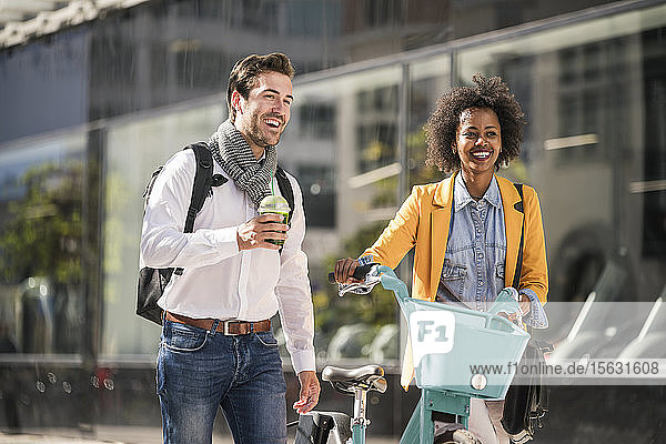 Glücklicher junger Mann und Frau mit Fahrrad in der Stadt unterwegs