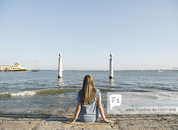 Rückansicht einer an der Küste sitzenden Frau  Lissabon  Portugal