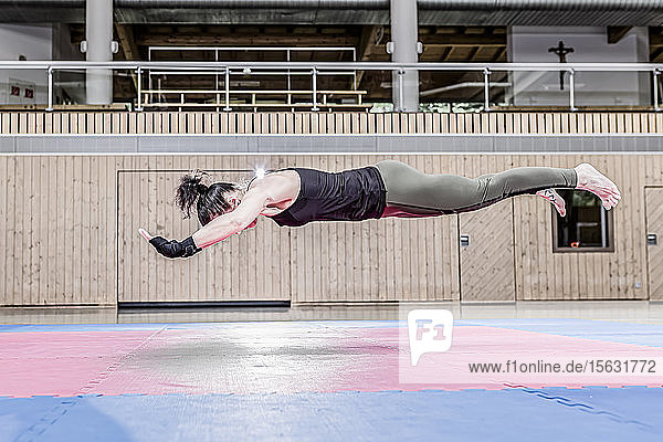 Woman exercising in sports hall floating mid-air
