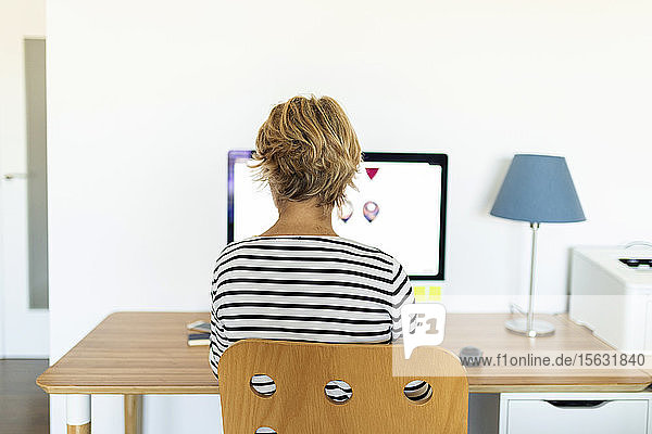 Rückansicht einer Wature-Frau am Desktop-PC im Heimbüro