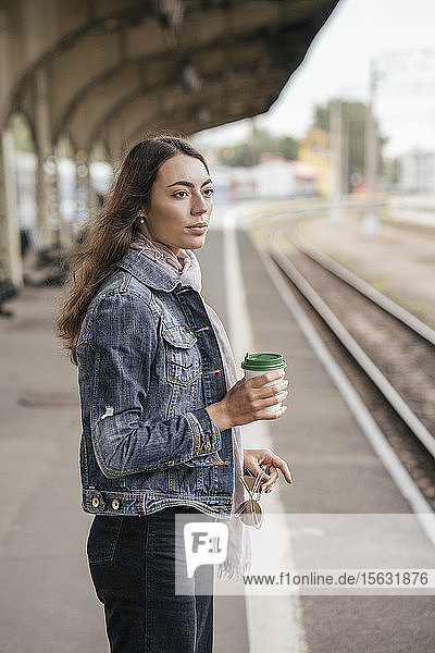 Junge weibliche Reisende mit Kaffee zum Bahnhof
