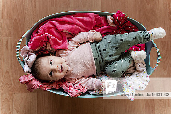 Kleines Mädchen im Wäschekorb mit zu reinigender Kleidung