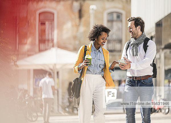 Happy young couple looking at smartphone in the city