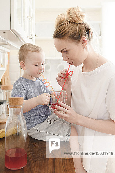 Mutter mit ihrem kleinen Jungen trinkt ein Glas Saft