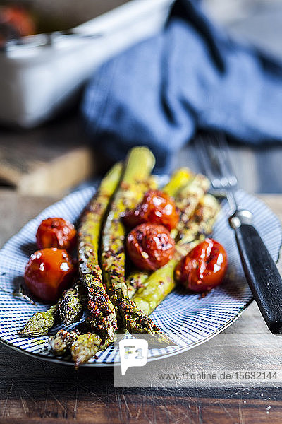 Gegrillter grüner Spargel mit Kirschtomaten auf einem Teller