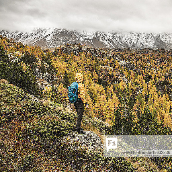 Wanderer steht und blickt im Herbst über das Alpenplateau Sondrio Italien