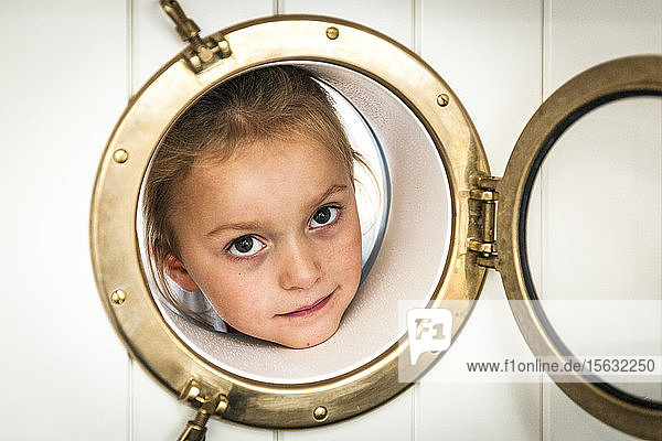 Portrait of girl looking through porthole