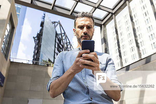 Serious businessman looking at the smartphone in the city  Berlin  Germany