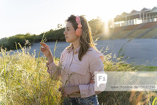 Junge Frau  die im Freien mit Kopfhörern Musik hört