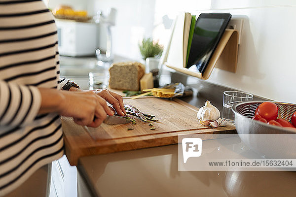 Nahaufnahme einer Frau  die zu Hause in der Küche kocht und Gemüse schneidet