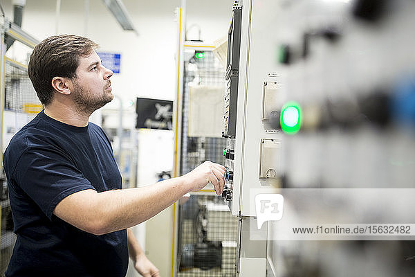Mann der in einer modernen Fabrik arbeitet und eine Maschine bedient