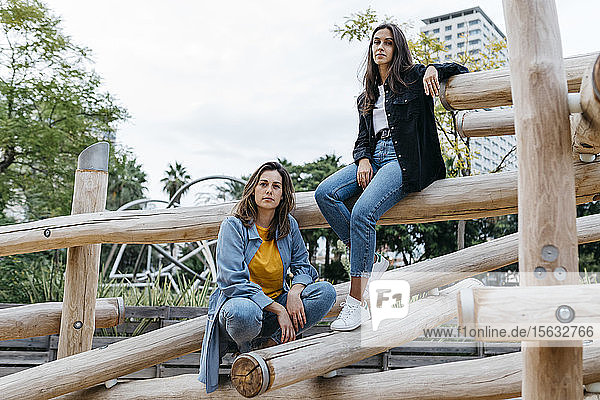 Two friends on playground sitting on jungle gym
