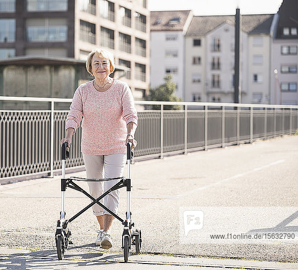 Ältere Frau mit Gehhilfe auf Rädern auf Fußgängerbrücke