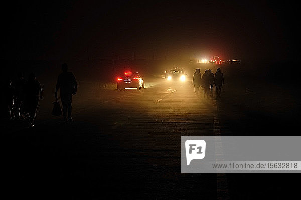 Portugal  Algarve  Cars passing silhouettes of four people walking along road in Cape Saint Vincent at night