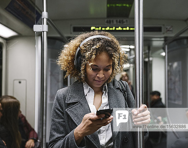 Frau benutzt Smartphone in der U-Bahn