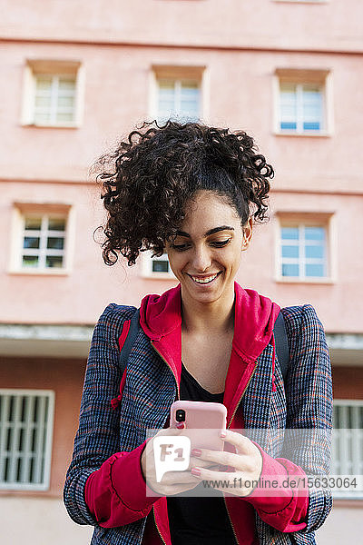 Porträt einer glücklichen jungen Frau bei der Benutzung eines Mobiltelefons
