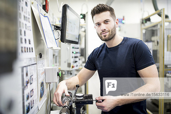 Portrait of a confident man working in a modern factory operating a machine