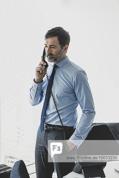 Serious mature businessman on the phone in office