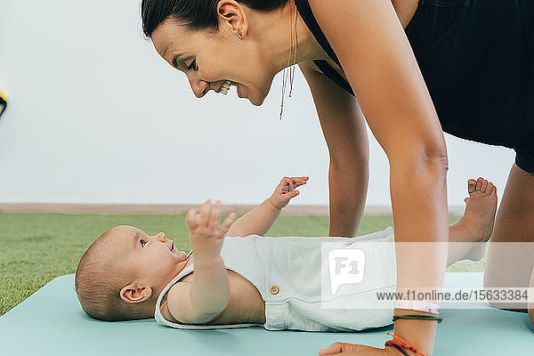Young mother and baby exercising on yoga mat