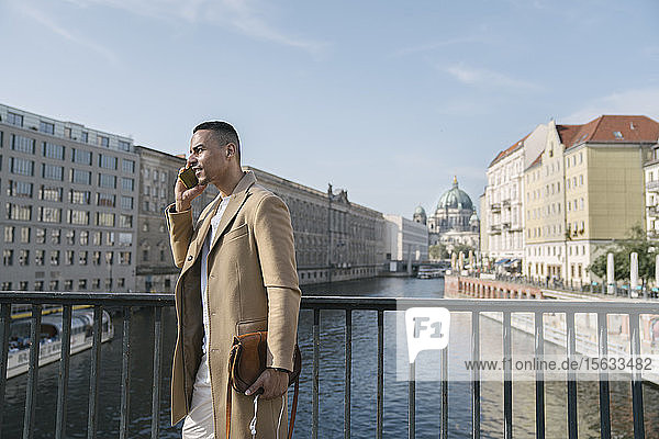 Geschäftsmann am Telefon auf einer Brücke stehend  Berlin  Deutschland