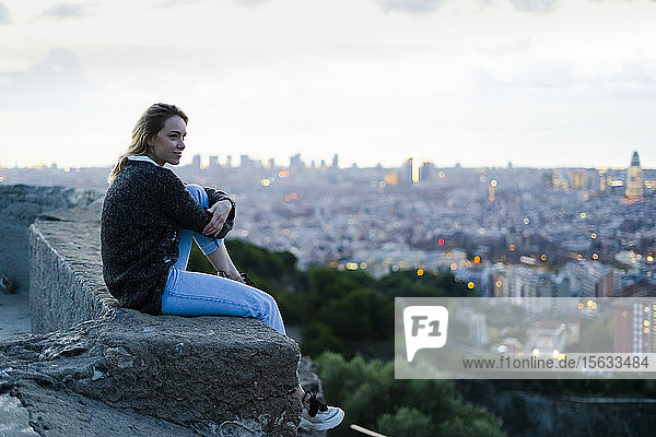 Junge Frau sitzt bei Sonnenaufgang über der Stadt  Barcelona  Spanien