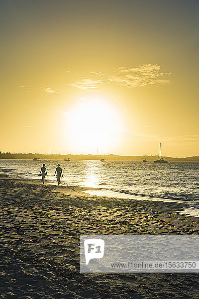 Silhouettenpaar beim Spaziergang am Strand von Grace Bay gegen den Himmel bei Sonnenuntergang  Providenciales  Turks- und Caicos-Inseln