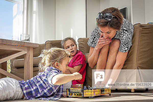 Mother playing with daughters in living room