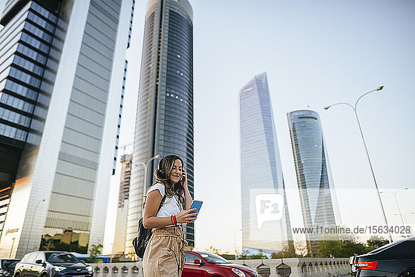 Junge Frau benutzt ein Smartphone mit Wolkenkratzern im Hintergrund