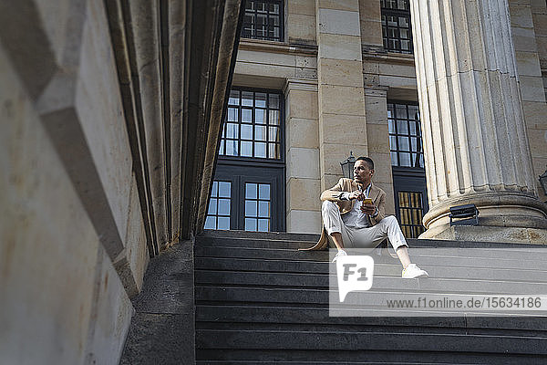 Geschäftsmann sitzt mit Smartphone auf der Treppe
