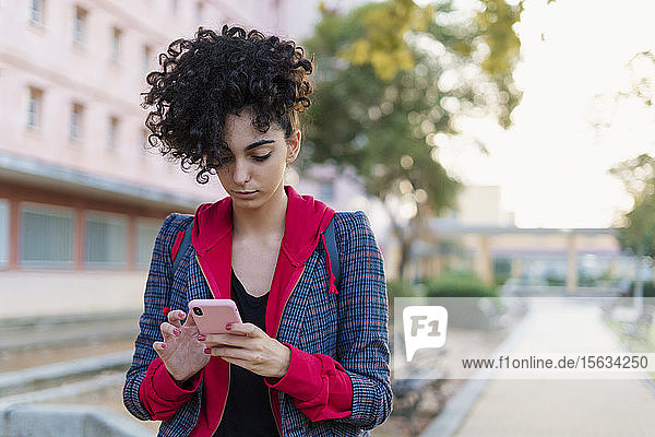 Porträt einer jungen Frau  die im Freien ein Mobiltelefon benutzt