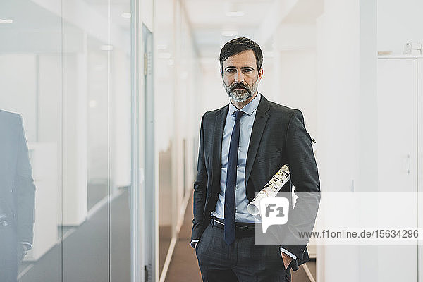 Portrait of serious mature businessman standing on office corridor