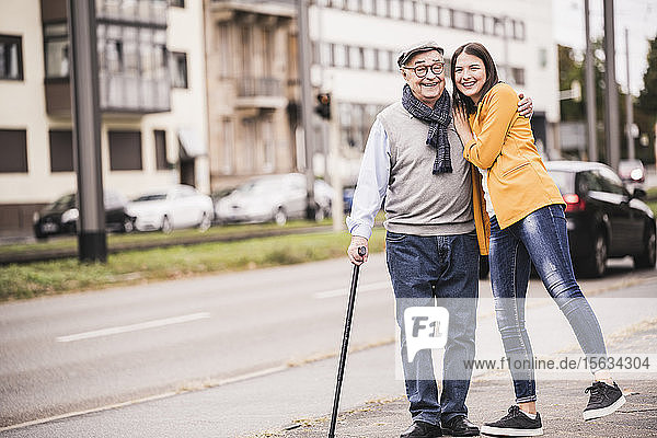 Porträt eines glücklichen älteren Mannes  der mit seiner erwachsenen Enkelin spazieren geht