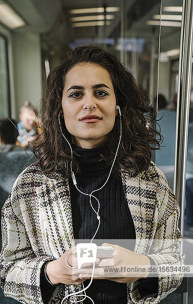 Portrait of beautiful young woman with earphones and smartphone on a subway