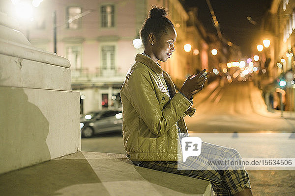 Junge Frau benutzt Smartphone in der Stadt bei Nacht  Lissabon  Portugal