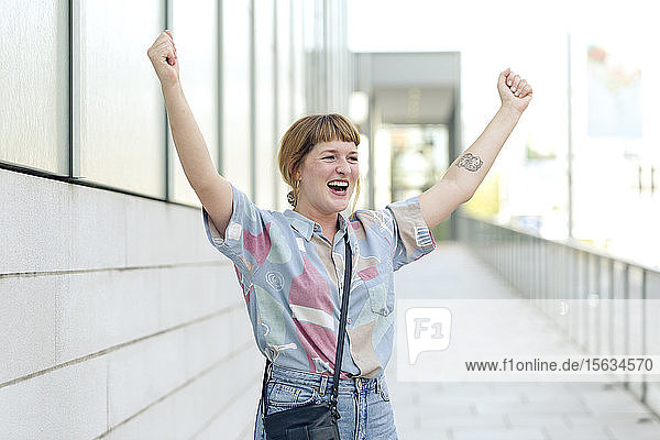 Portrait of happy young woman raising hands