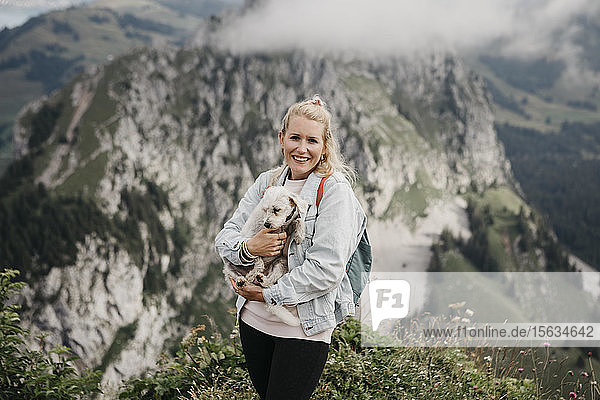 Junge lächelnde Wanderin mit Hund auf dem Aussichtspunkt