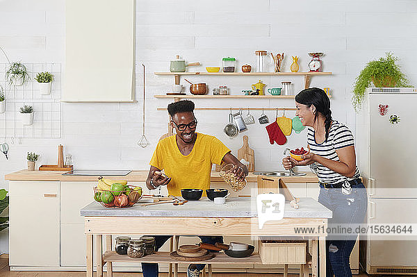 Multiethnisches Paar lacht  frühstückt gemeinsam in der Küche
