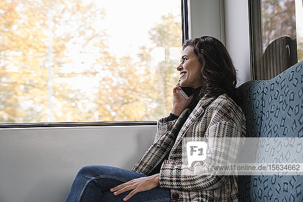 Smiling young woman on the phone on a subway