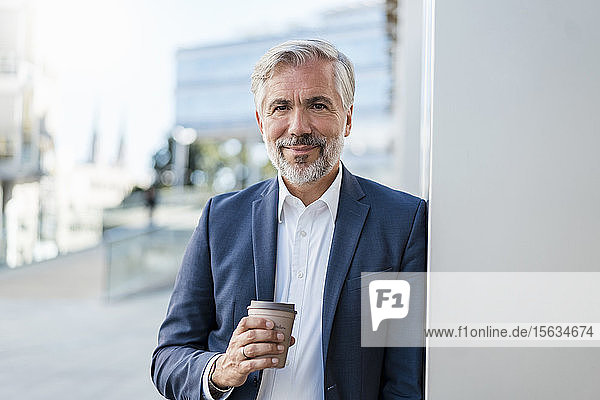 Portrait of mature businessman with takeaway coffee in the city