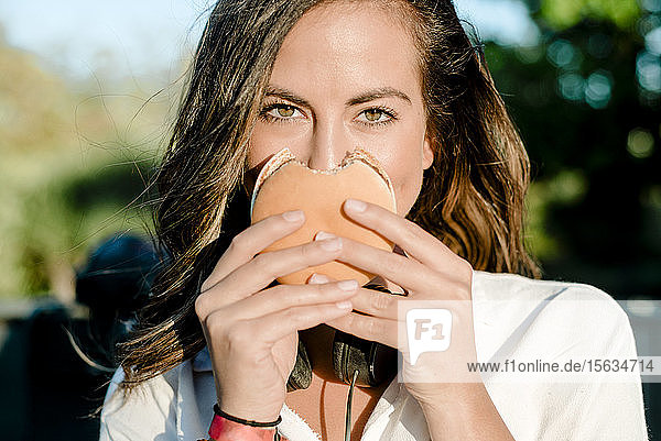 Junge Frau  die ihr Gesicht mit einem Hamburger bedeckt