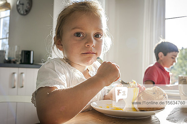 Portrait of girl eating a boiled egg at dining table