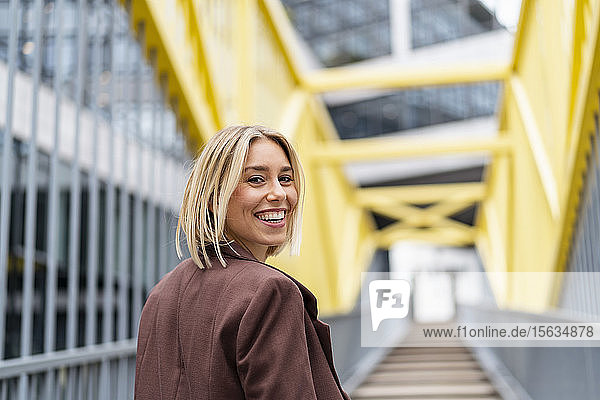 Porträt einer glücklichen jungen Geschäftsfrau auf einer Brücke in der Stadt