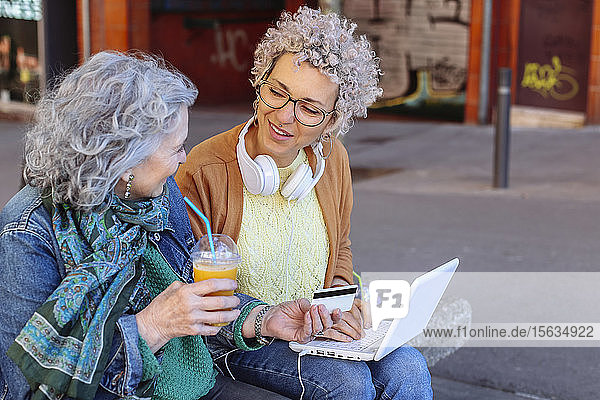 Ältere Mutter mit ihrer erwachsenen Tochter beim gemeinsamen Online-Einkauf in der Stadt